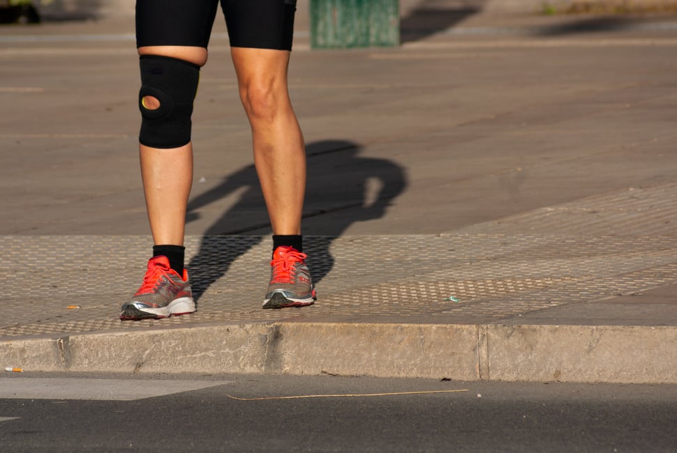 Runner woman that suffered a knee accident and now wears knee brace on the sidewalk